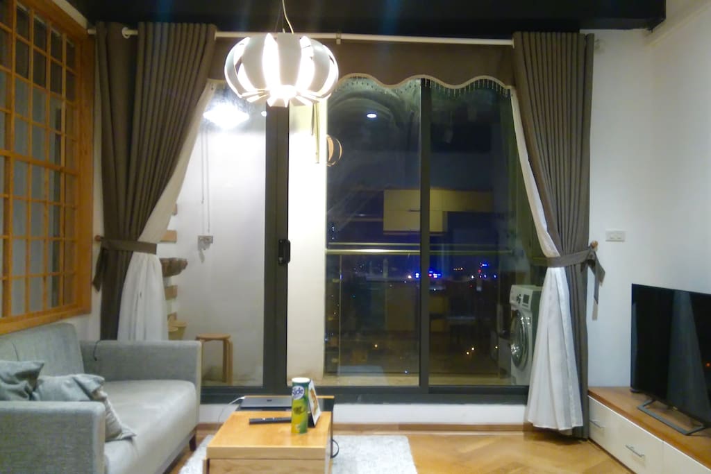 Living room with sofa, tea table, TV and the glass balcony