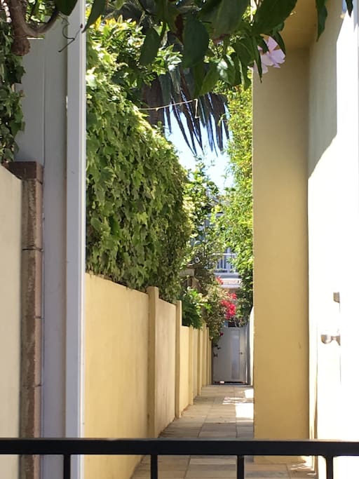 After you open the back gate near the cars with your key, you'll see this long corridor to the other side of the property. The apartment is up the staircase to the left.