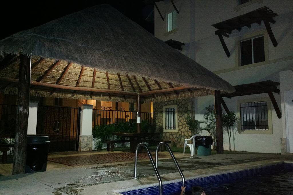 Palapa en zona de alberca con iluminación nocturna