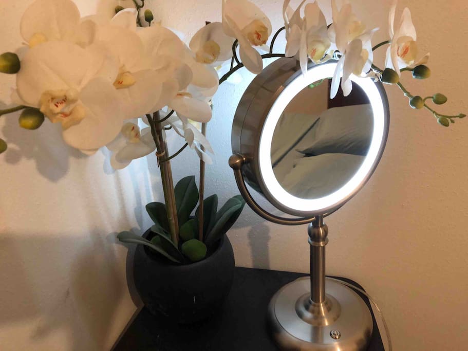 the comfy queen bed is reflected in the vanity mirror with LED light