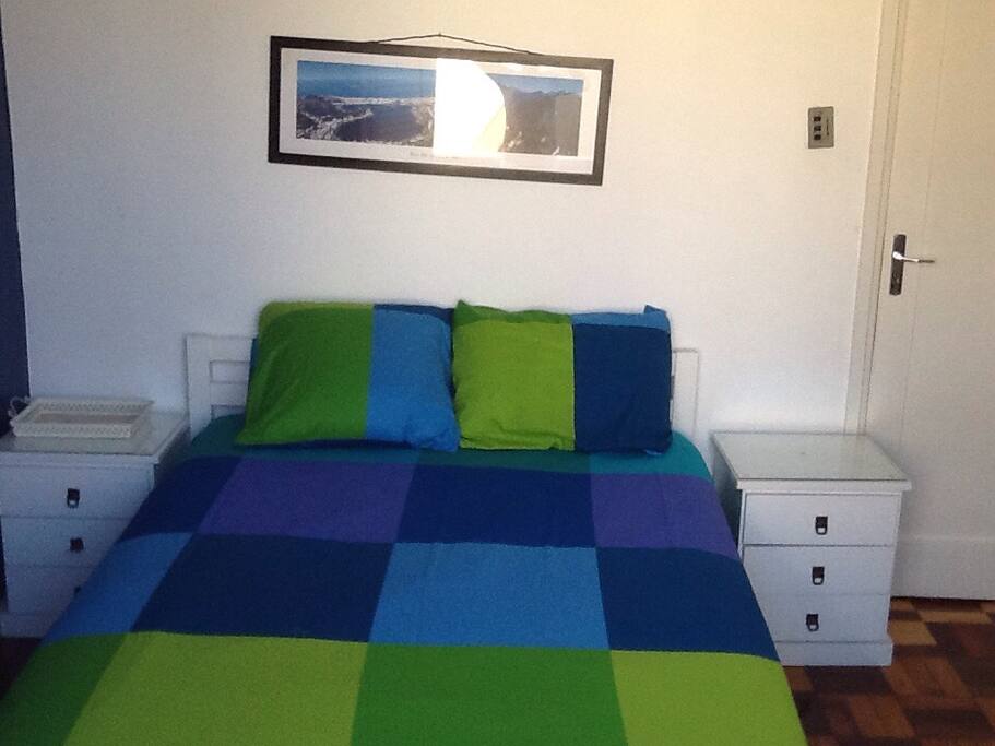 Este é um quarto com cama de casal. Ele tem ar condicionado, um armário e uma porta - janela para pequena varanda.