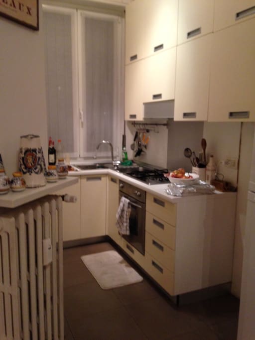 Open/ separate kitchen with stove top and oven, full size fridge, dishes, pots and pans, and a window