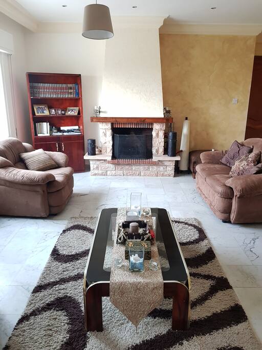 Open living room with a three piece sofa set, fireplace, large TV and surround system.