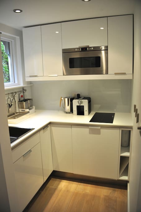 Kitchen with hob, refrigerator, microwave, tea kettle, Nespresso machine, and of course dishes and cutlery.
