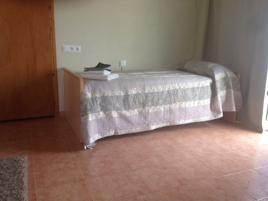 Cama individual, toallas y zapatillas