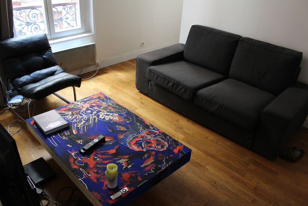 Espace salon comprenant TV, canapé et Fauteuil, donnant sur une allée privée très calme