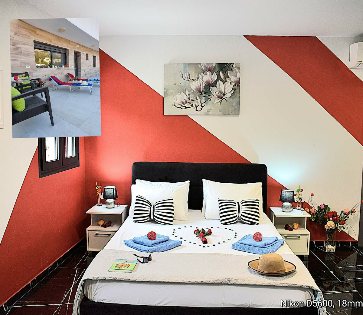 A spacious sleeping area is highlighted by a stylish black bed with white linens. Decorative pillows add a touch of color, while bedside tables are equipped with lamps. A floral artwork is mounted on the wall, complementing the room's vibrant geometric design.