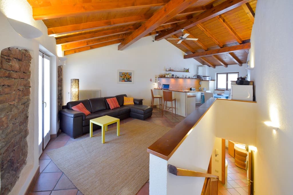 Ampio soggiorno luminoso con cucina a vista e tetto mansardato