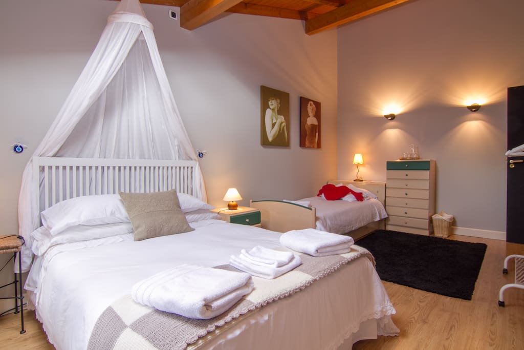 Una habitación abuhardillada, con altos techos de madera, una ventana y una claraboya