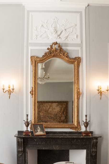 Marble fireplace and lovely ornate mirror above in a French apartment in the South of France with light grey walls and beautiful moldings. #fireplace #luxurious #French #apartment