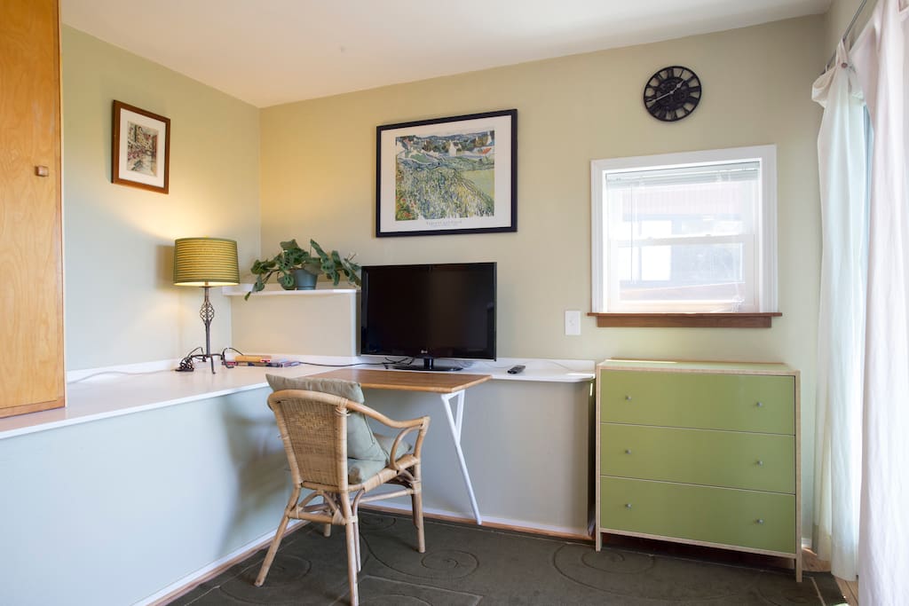 Room features a fold-up desk, TV, dresser and armoire with hangers
