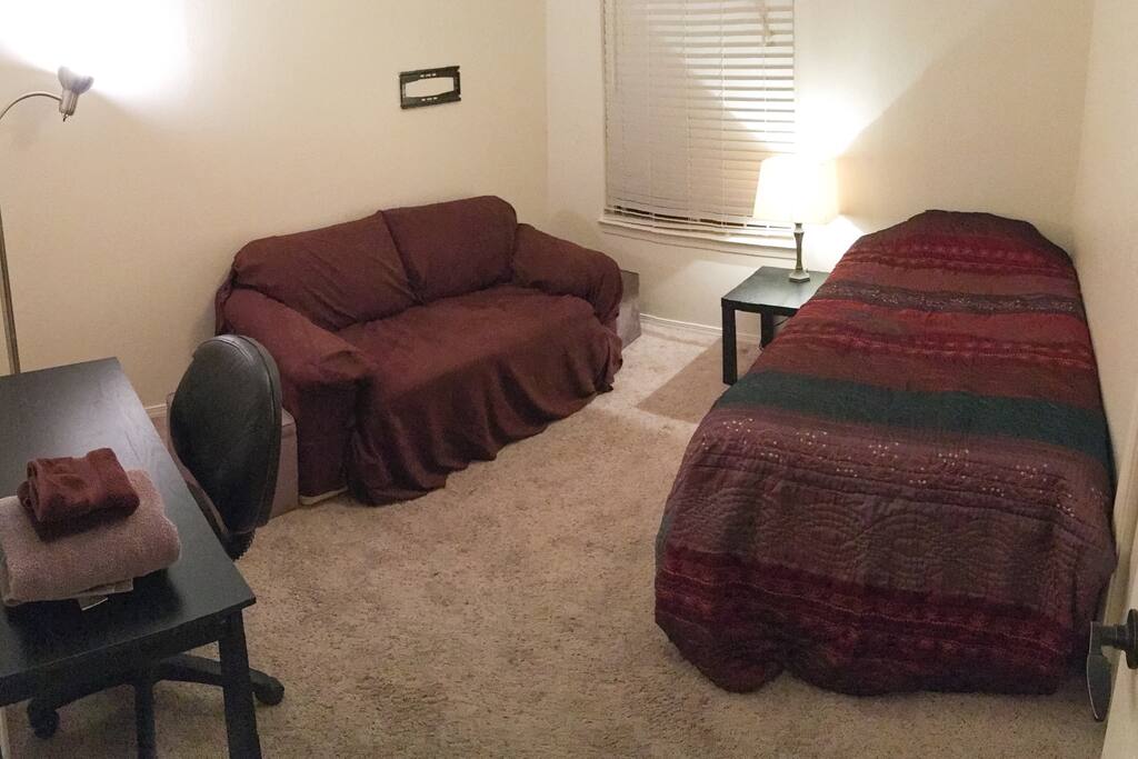 Private bedroom with plenty of clean blankets and fresh sheets with a desk and small couch