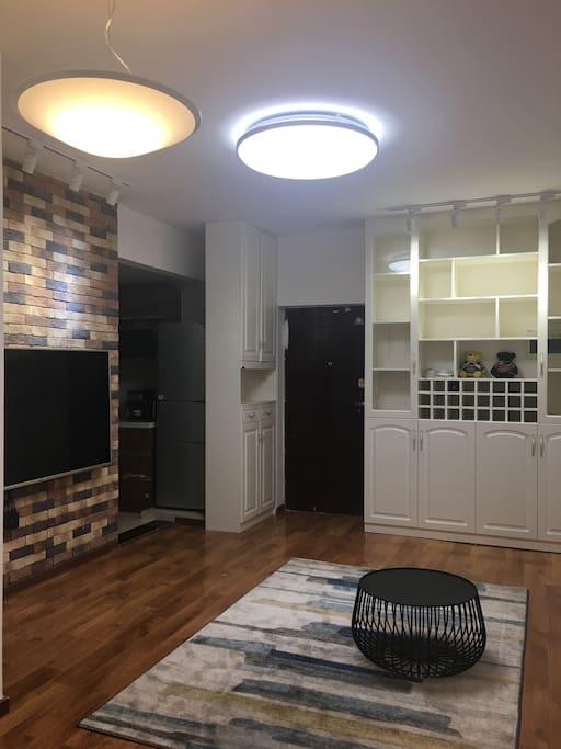 Living room, connected with an open kitchen, big size TV, nice spotlights at both the wine wardrobe and the TV wall