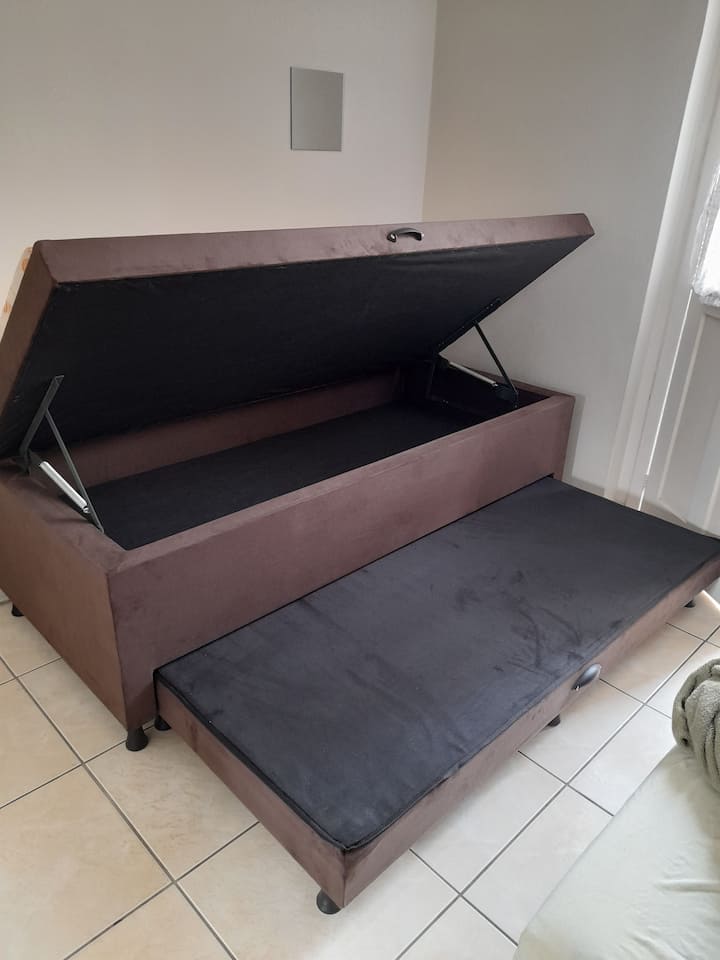 Lit avec coffre de rangement et couvertures.