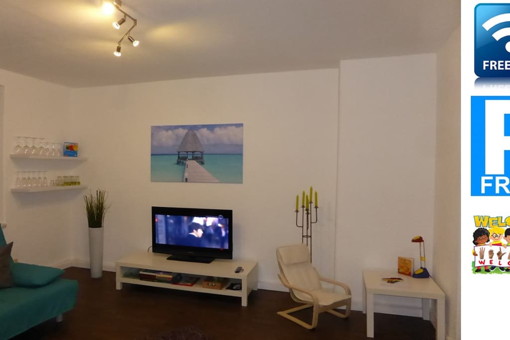 Wohnzimmer mit Fernseher und Kinderecke.