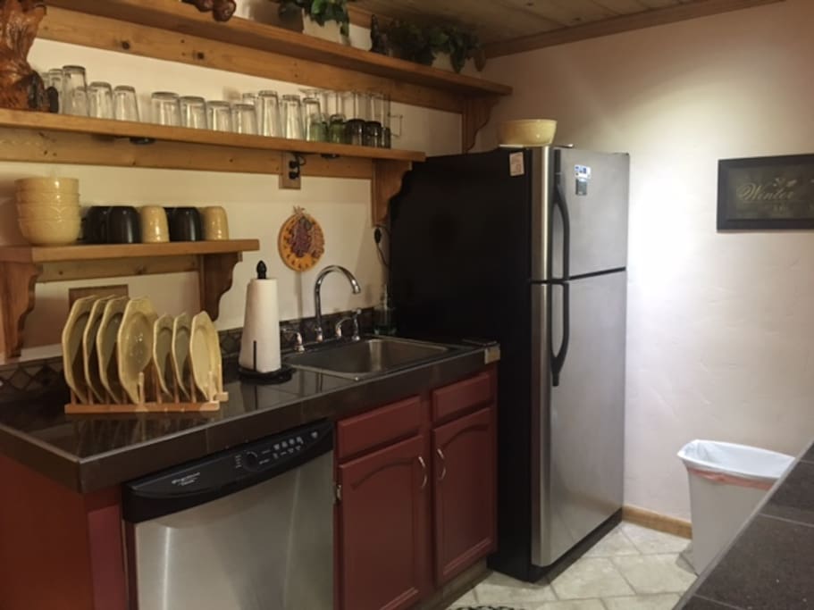 Full size kitchen stocked with plates, glasses, silverware, cookware and supplies