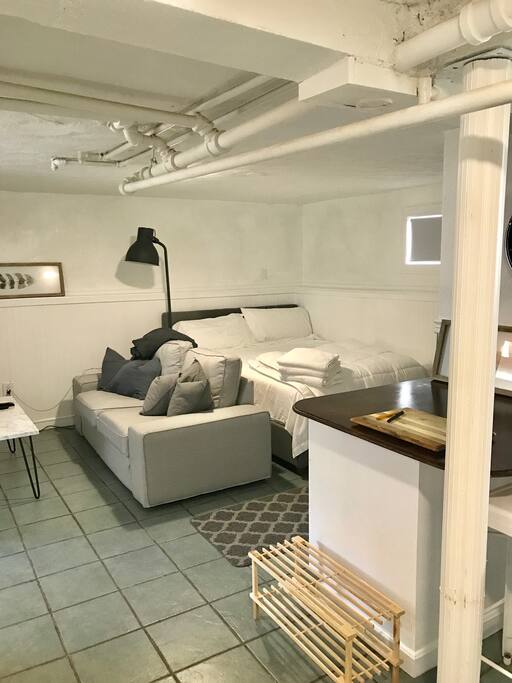 Cozy queen size bed with memory foam mattress tucked in corner of unit.