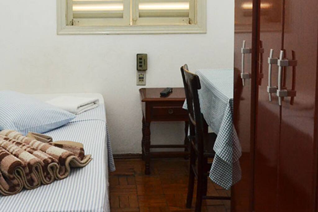 Quarto individual com banheiro compartilhado.