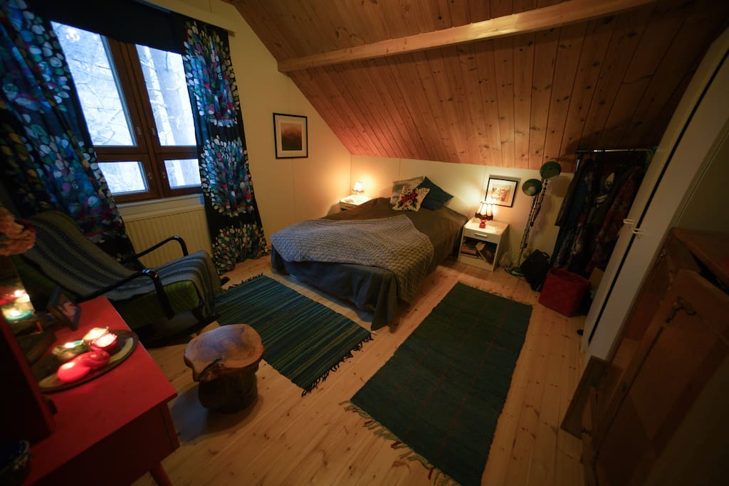 Cozy, retro spirited bedroom upstairs with pine wood floor and ceiling panels.