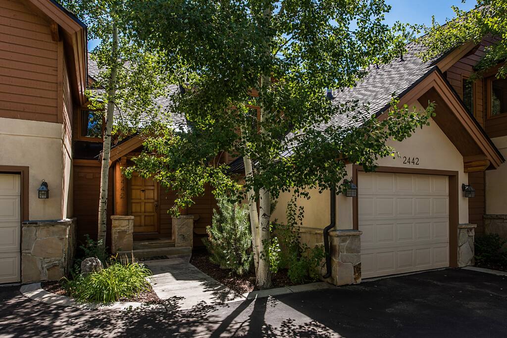 Front of home in summer, garage includes ski racks