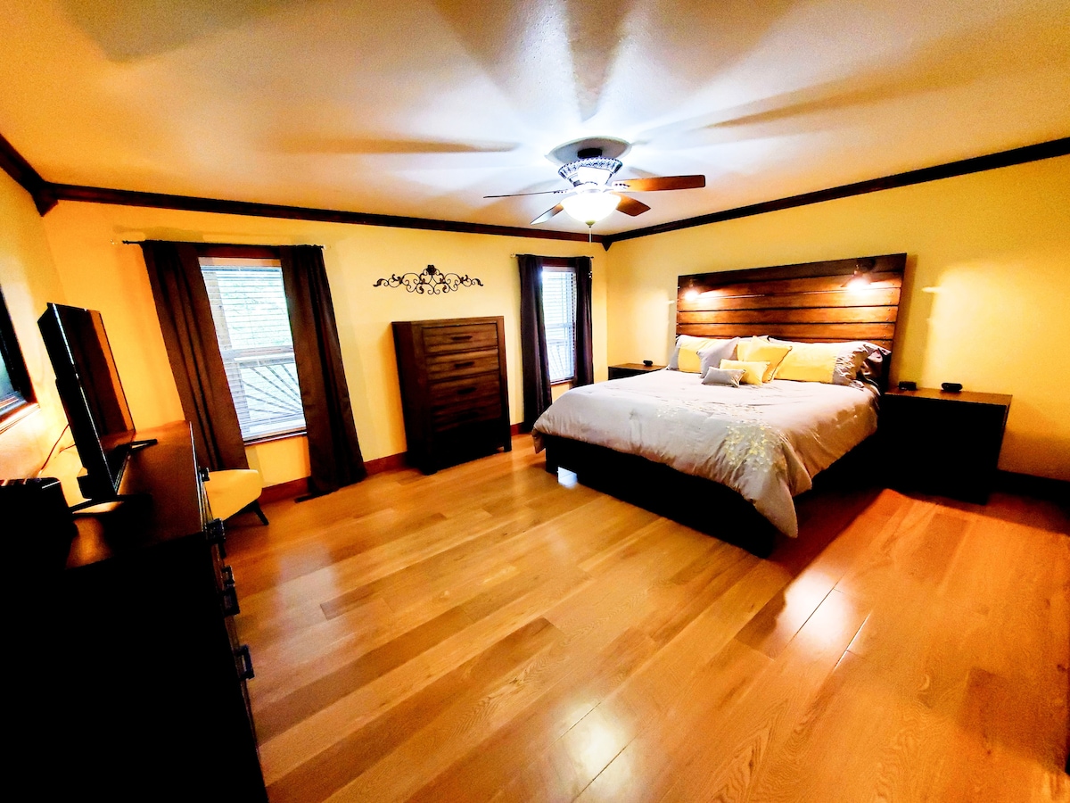 ห้องนอนใหญ่พร้อมที่นอนคิงส์ดาวน์หรูหราใหม่เอี่ยม ช่องเสียบ USB บนโต๊ะข้างเตียงและเครื่องเสียงแต่ละเครื่อง ไฟอ่านหนังสือที่มีปุ่มควบคุมอยู่บนหัวเตียง 