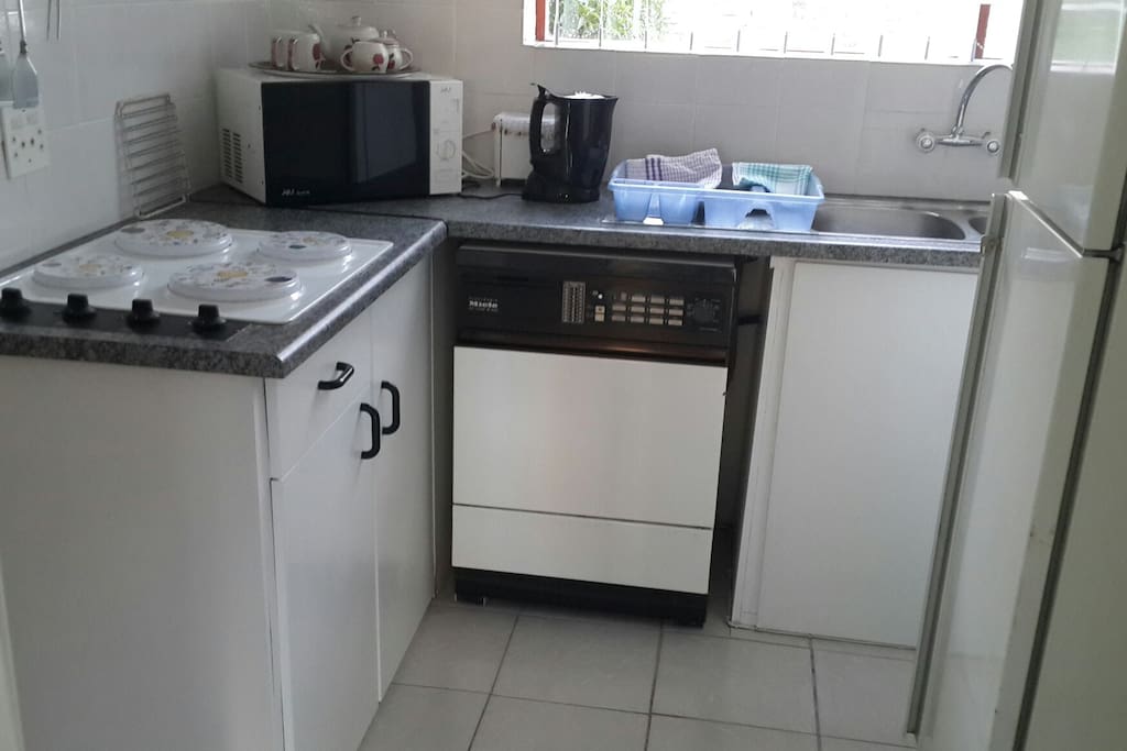 Kitchen with washing machine, microwave, 4 plate hob, fridge.