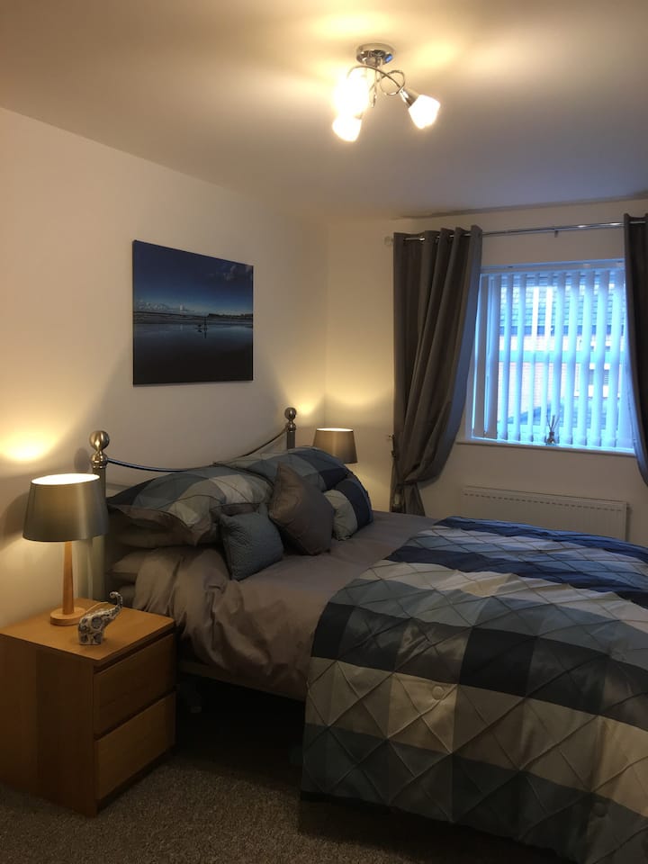 'Bushmills' is finished in blue tones with a king size grey metal bed. A canvas of the West Strand Beach, Portrush complements the bedding.
A wall mounted flat screen HD TV with DVD player and ample storage complete the room.