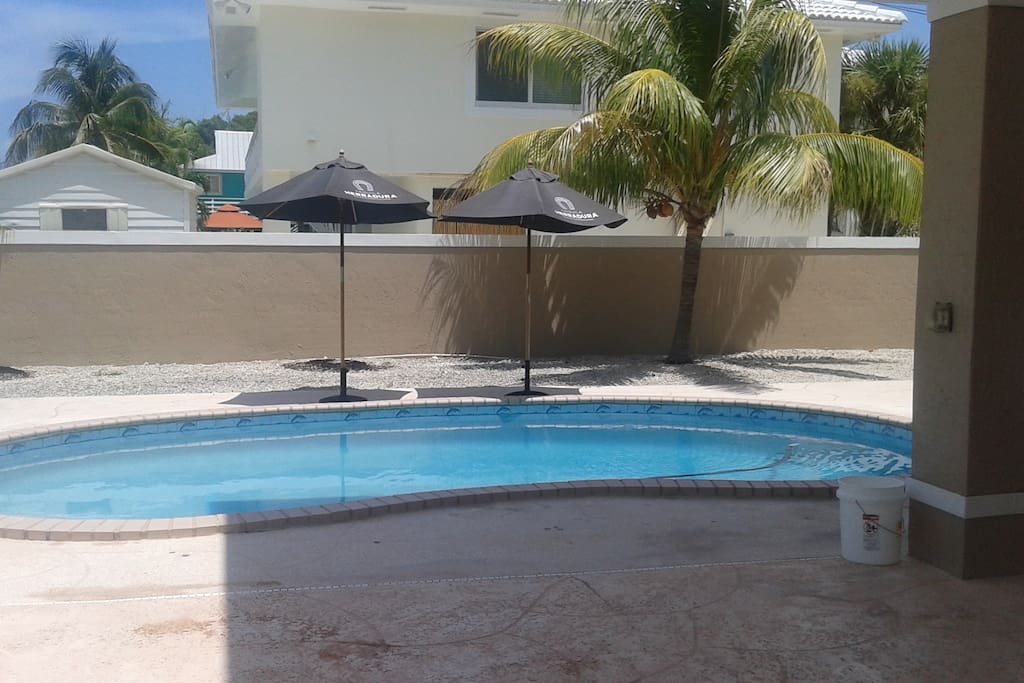 Pool down stairs in breezeway area equipped with table, hammock, lounge chairs and tv
