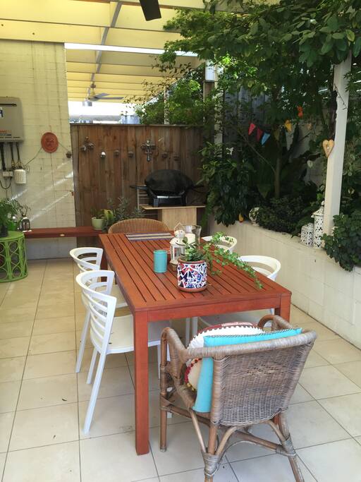 Courtyard with BBQ and covered area and open area onto a grassy area.