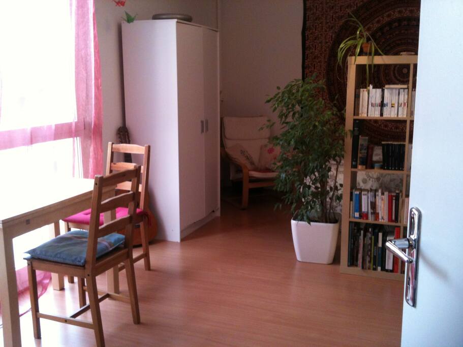 Coin salon, très lumineux et vue sur les toits, petite table pour manger, bureau (non visible sur la photo) pour travail à l'ordinateur. Derrière l'étagère, le coin chambre avec fauteuil et lit 2 places.