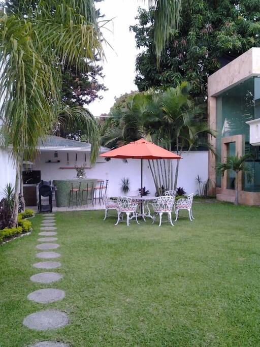 Palapa con su barra con sus sillas asador, mesa de jardín sombrilla , todo listo para hacer carne asada.