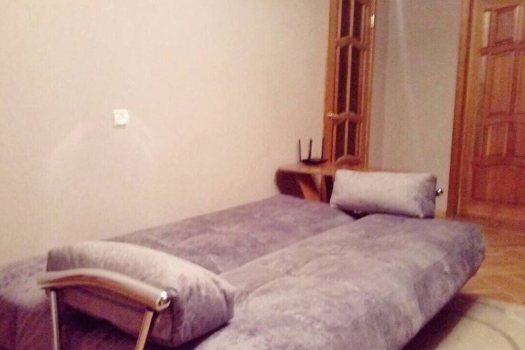 Large room of 18 square meters with a large sofa, a TV, a wardrobe and a work table