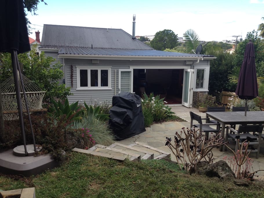 Private backyard with BBQ, double hammock, table and chairs, bifold doors opening up house to deck