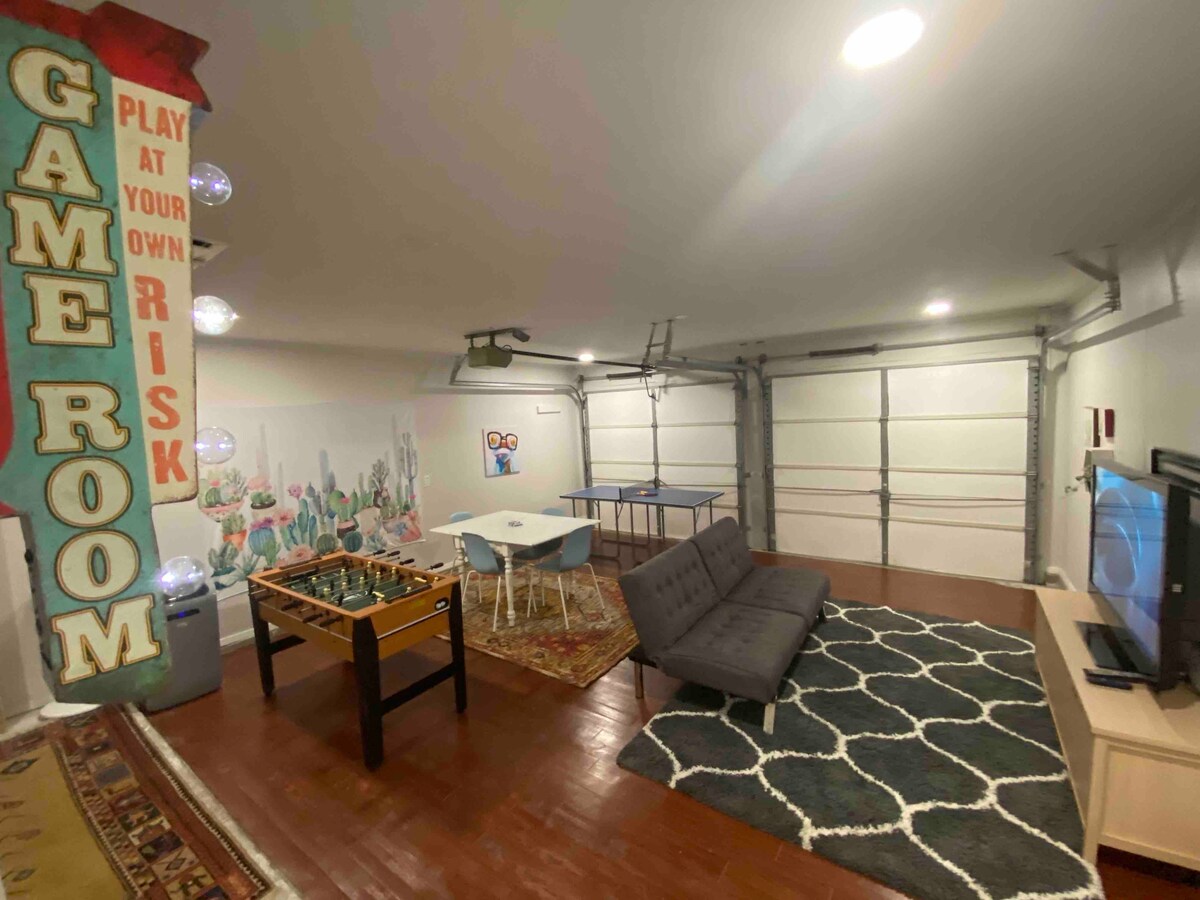 Chumba cha Mchezo kilichojaa michezo ya ubao na kilicho na ubao wa kielektroniki wa dart, meza ndogo ya mpira wa magongo/mpira wa magongo wa hewa, meza ndogo ya ping pong na meza ya kadi iliyo na kadi. 