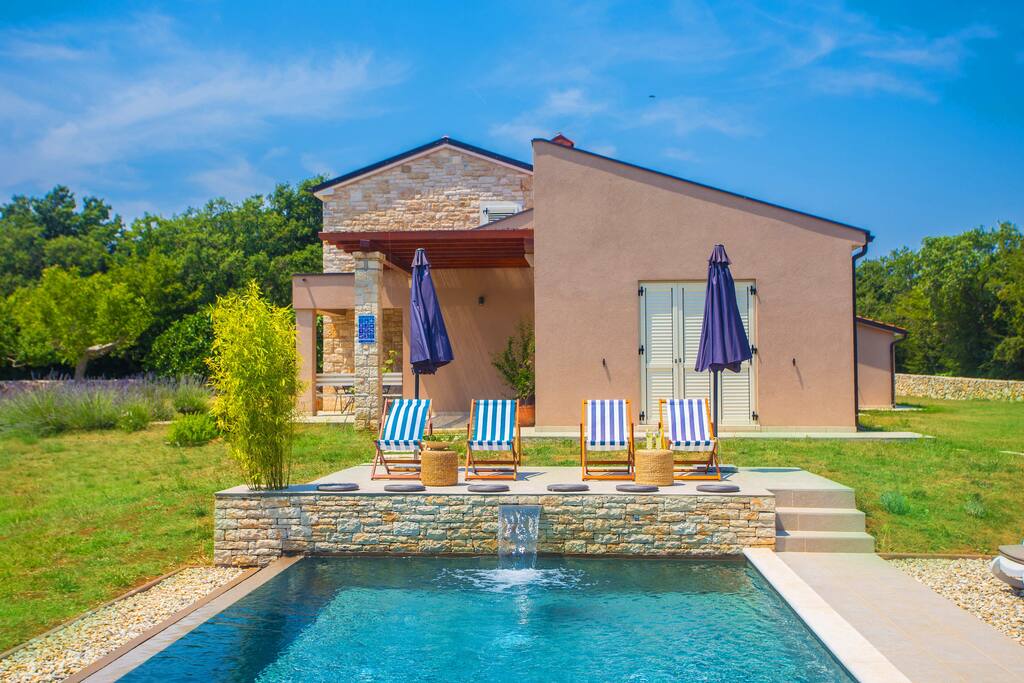 Natural pool immersed in greenery of a huge garden with stone house with modern touch