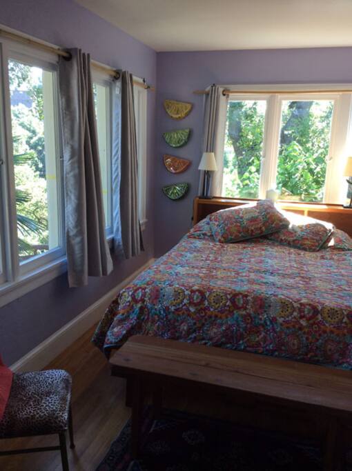 A queen bed surrounded by windows is light and airy.