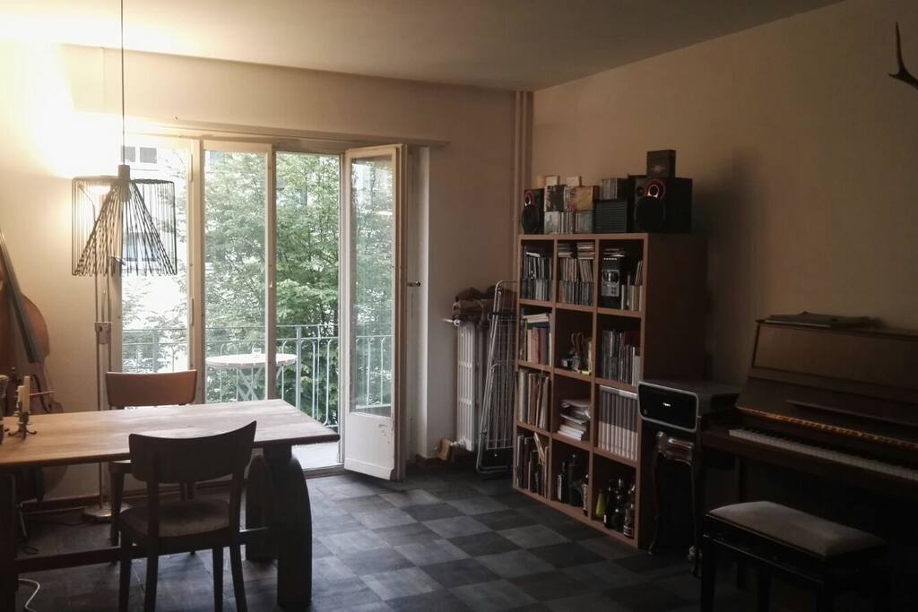 Living room with piano (!), sofa, table and balcony