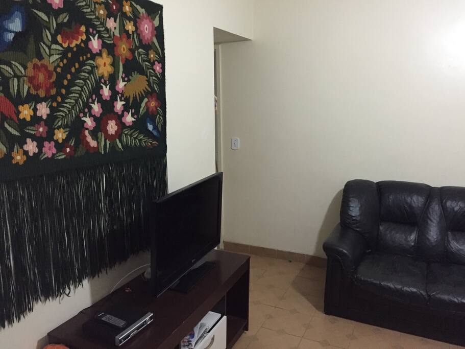 Sala com 2 sofás, sendo um sofá cama, ventilador e tv de 32
