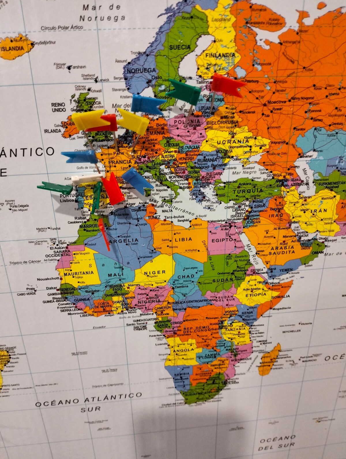 A colorful map of the world is displayed, highlighting countries in various hues. Numerous pins in different colors are inserted in locations across Africa and Europe, indicating points of interest. The map provides a clear view of geographical borders and major bodies of water.