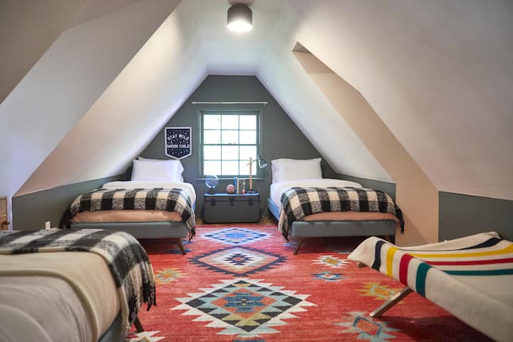Loft bedroom with vintage camping cot inspired by Wes Anderson.