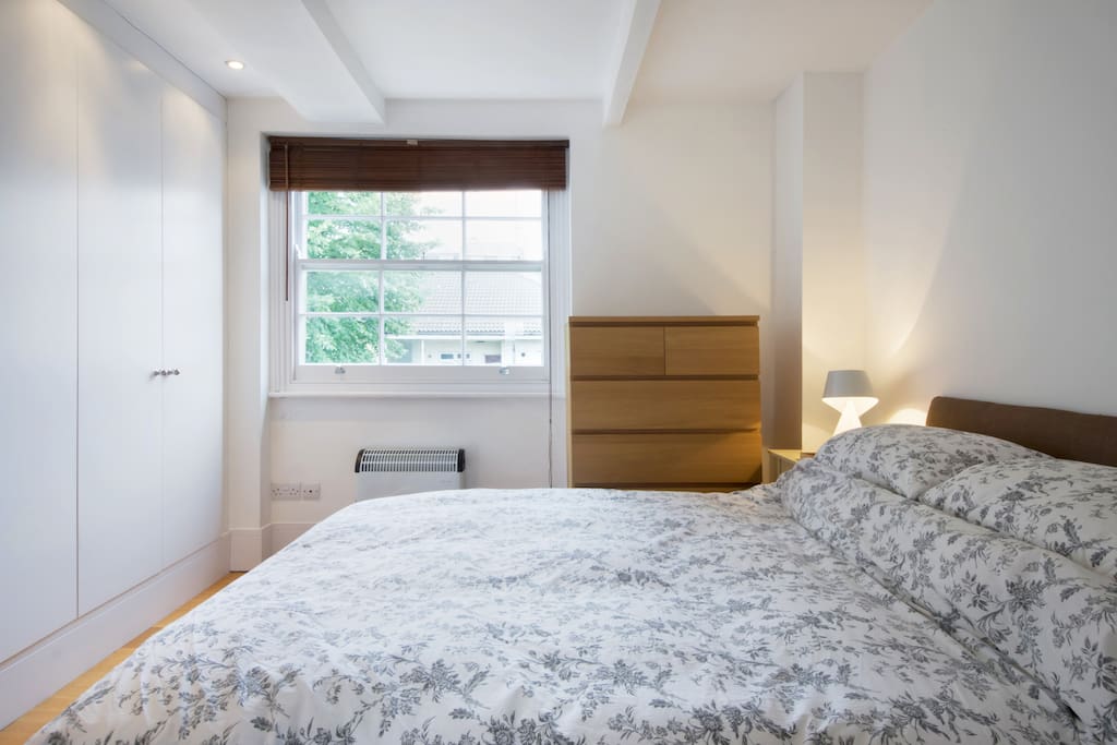 Double bed with large mirror and window letting in morning sun