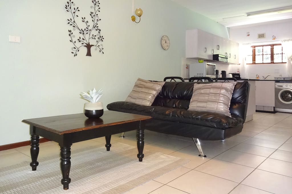 Open plan lounge with couch, two chairs, coffee table and TV