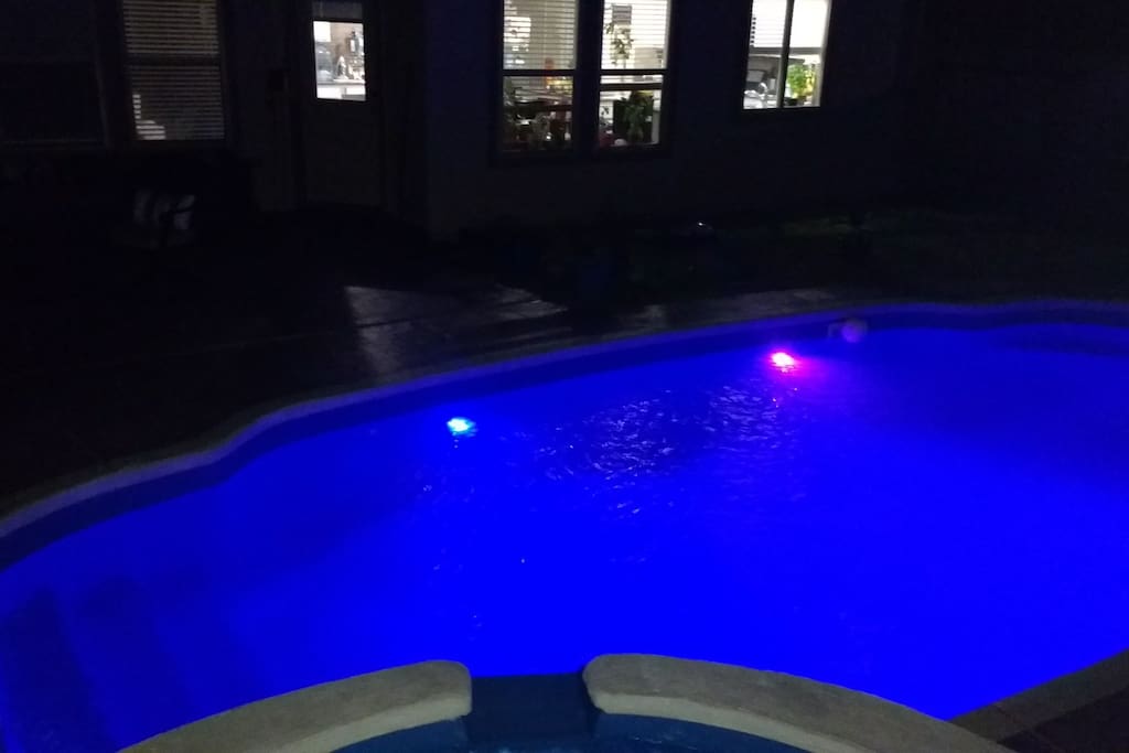 The pool at night with a view of the kitchen in the background