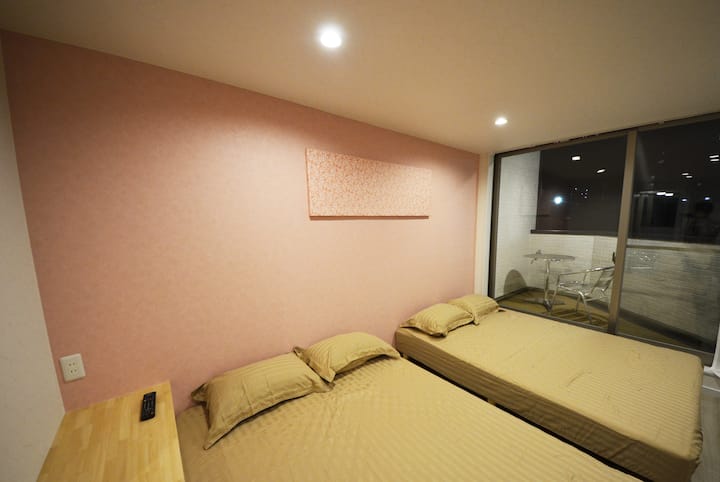 Bedroom 1 (2nd Floor):
There are 2 full double size low beds with mattress in one bedroom for up to 4 persons. Low bed is very good from avoiding a child hits the floor from falling out of bed at night. You can also combine 2 double beds together for a super big bed. TV is also available in this bedroom. A flexible TV mount is installed, which allows you to adjust the angle (left right up down) easily. There is a huge glass door which you can access to the balcony.

Bedroom 1 (2nd Floor)
There are two double beds available for up to four people to rest in this room.
It is a low bed (low bed), so it is safe if your child falls out of bed in the middle of the night.
Each bed can also be moved, so if you combine the two, you can use it as a huge bed.
There is also a TV with a movable mount, so you can adjust the orientation up, down, left and right so that you can watch while sleeping.
There is also a large glass window that can go out to the balcony.