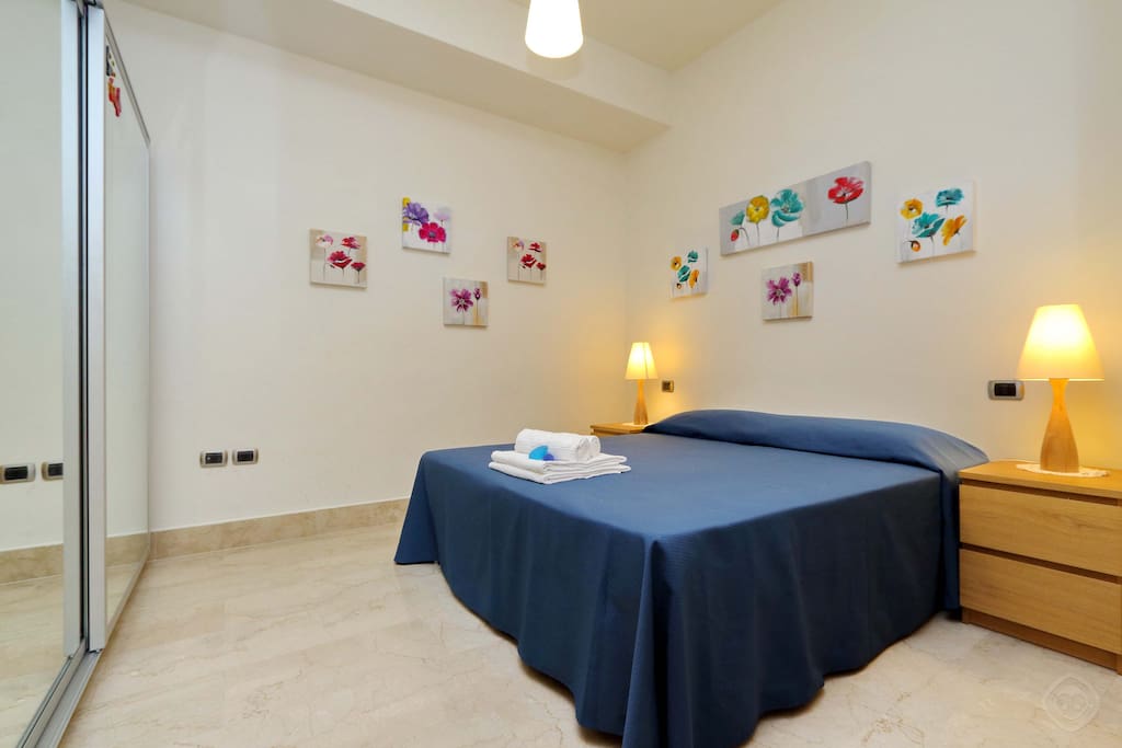 The inviting bedroom contains a double bed with bedside cabinets and storage cupboards.