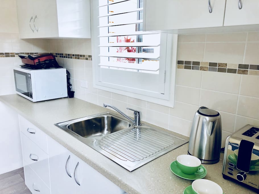 Kitchen/laundry with microwave, grill, kettle, toaster and washing machine