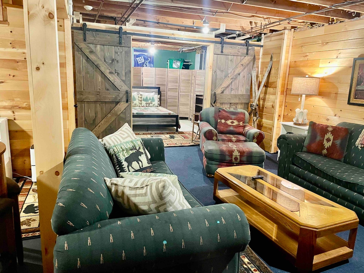 Djelomično dovršen prizemni/ugradbeni podrum s četvrtom spavaćom sobom smještenom iza kliznih vrata staje. Jedan od kauča je kauč za spavanje.