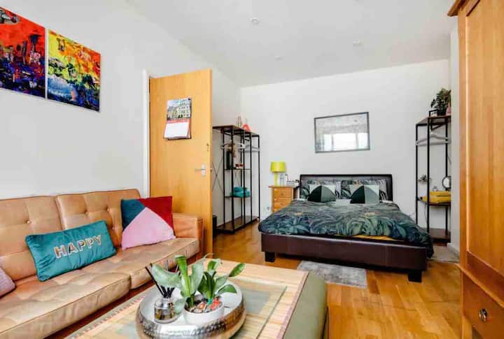 Dhomë e madhe vizitorësh me divan dhe televizor më vete. 