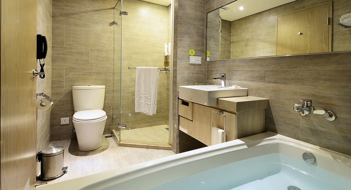 The modern bathroom includes a walk-in shower with glass enclosure, a spacious bathtub, and a toilet. A large mirror above the sink reflects the clean lines of the cabinetry. Neutral-toned tiles create a calming atmosphere throughout the space.