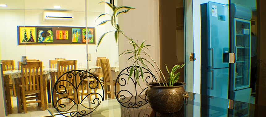 A dining area is visible, featuring a large table surrounded by wooden chairs. Artwork adorns the wall, while a potted plant adds a touch of greenery to the scene. A modern refrigerator is situated nearby, reflecting the well-equipped environment.